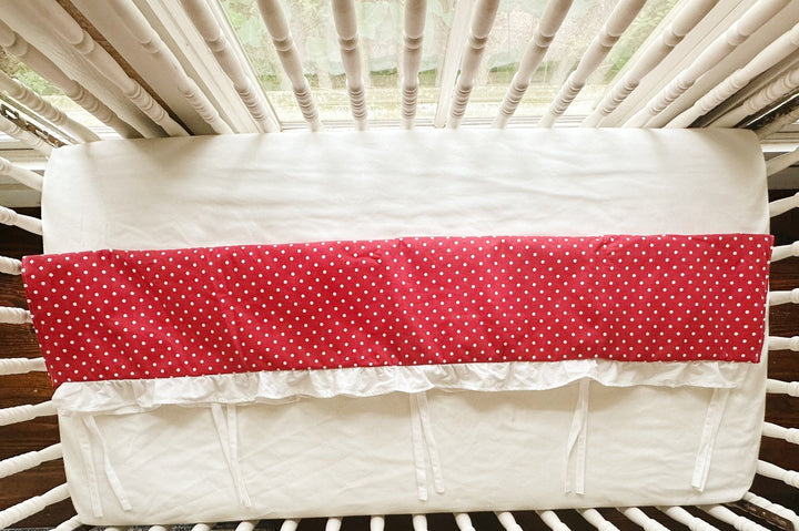 Overhead view of the rail cover folded over the crib rail, showing the plain white back panel