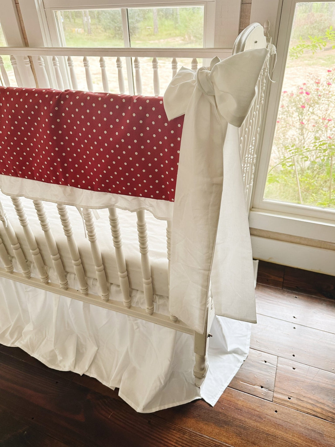 Side view of the polka dot print running the length of the long crib rail above the white skirt