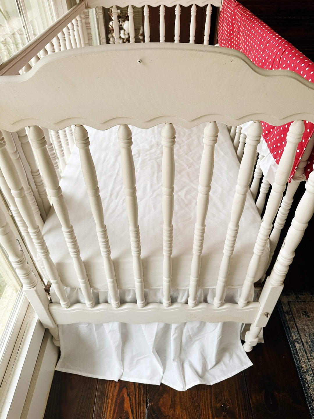 Looking down past the scalloped headboard at the white sheet and gathered white skirt