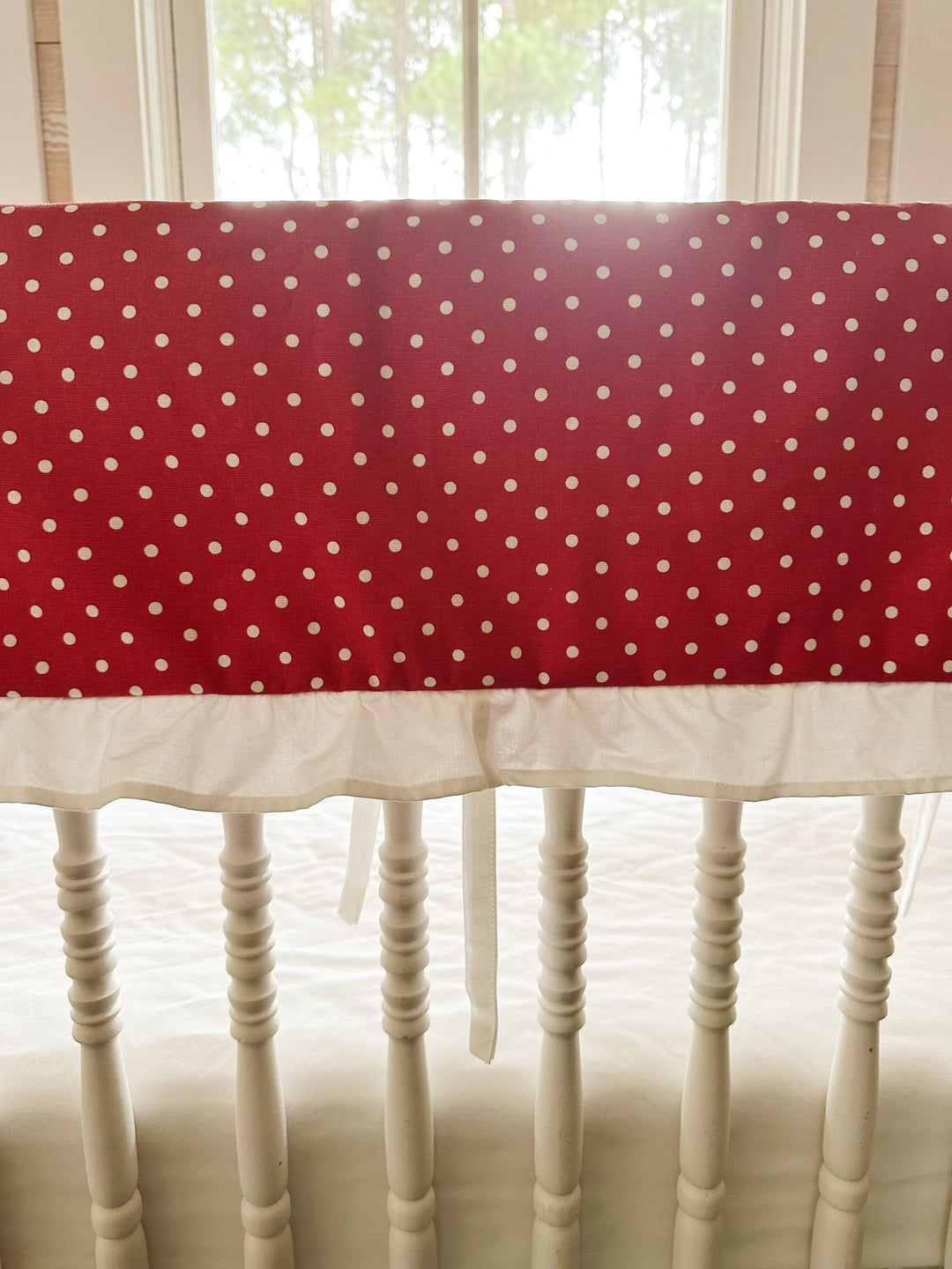 Close view of the small white dots on deep cherry red cotton above the gathered white ruffle
