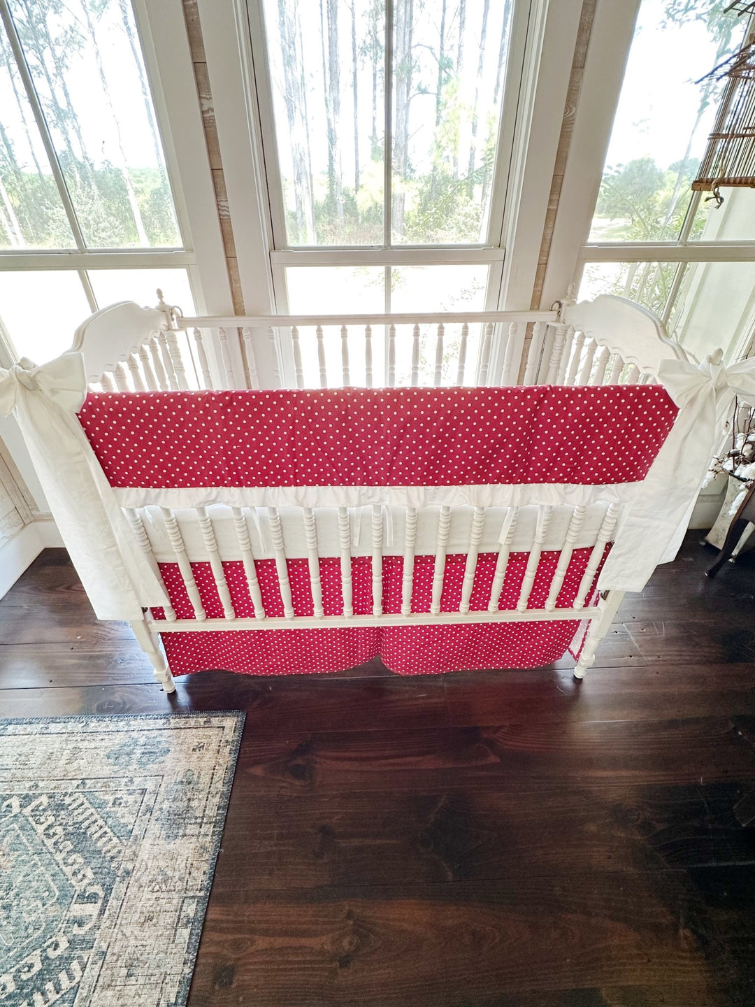 Cherry red and white polka dot ruffled crib rail cover with a matching dotted tailored skirt and two white bows