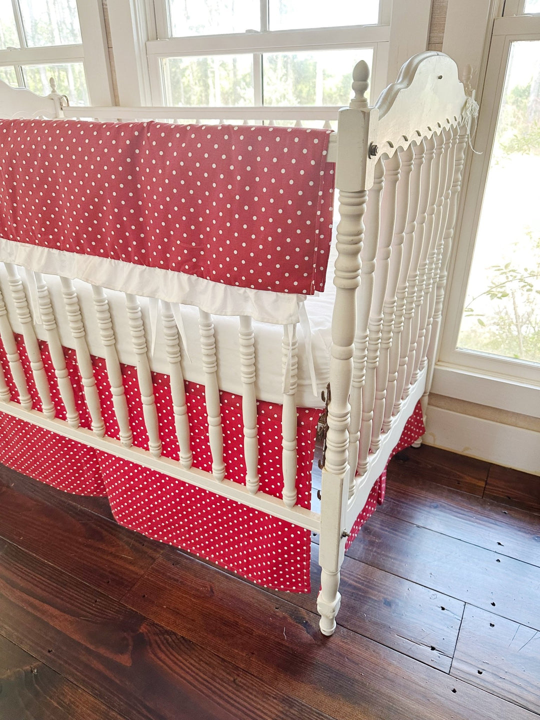 Corner view from the head of the crib, the polka dot rail cover folded over the long rail