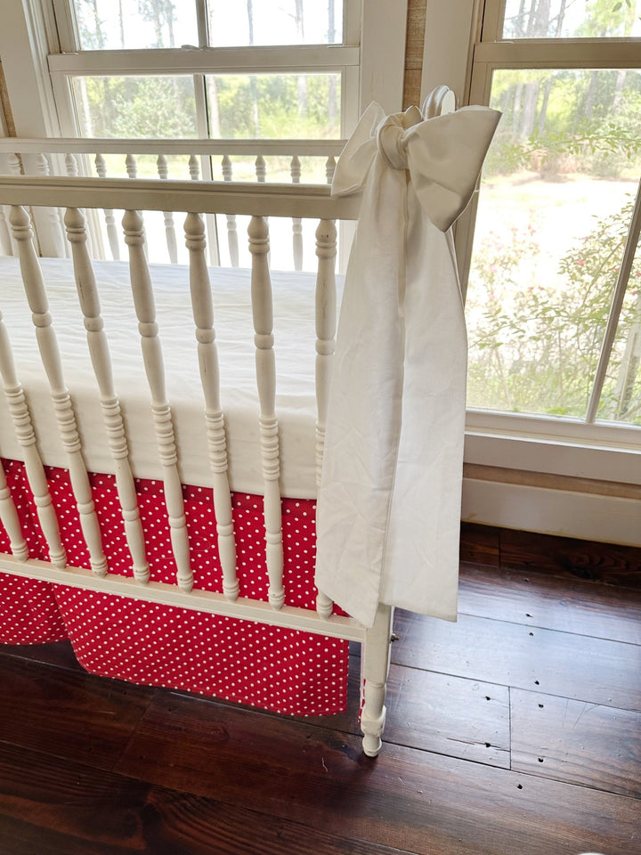 A white sash tied at the corner post, its tails falling past the dotted skirt toward the floor