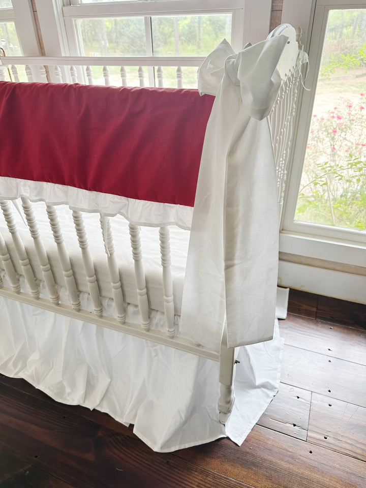 Side view of the solid red panel and gathered white ruffle above the white farmhouse crib skirt