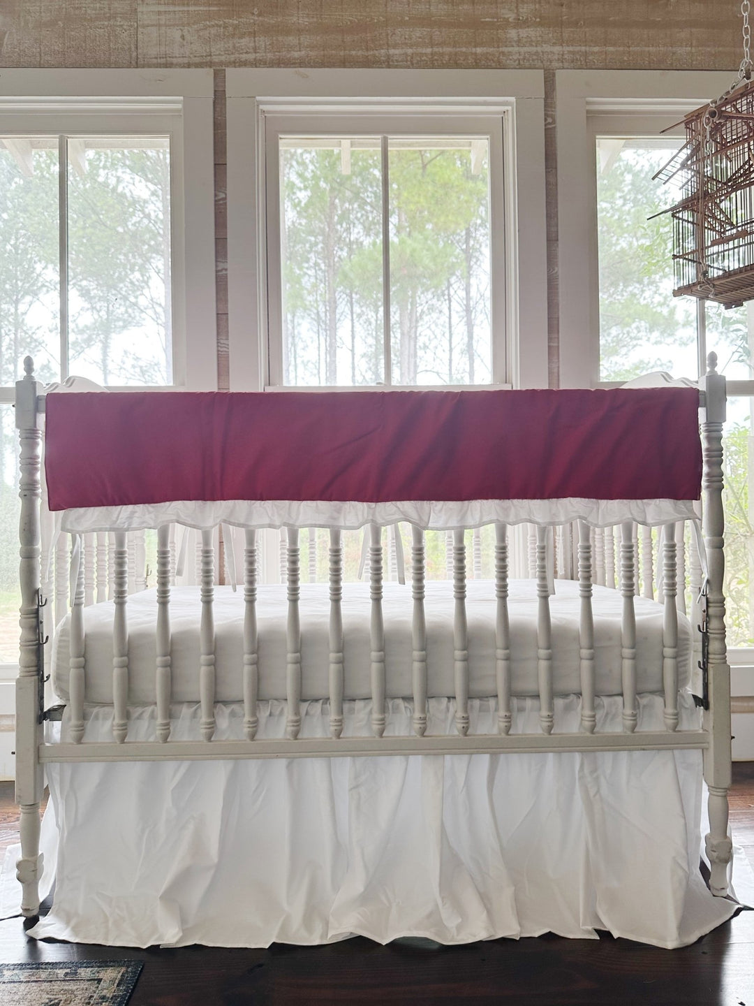 Bright red ruffled crib rail cover with a white ruffle above a gathered white farmhouse crib skirt, no bows