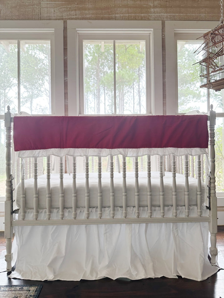 Bright red ruffled crib rail cover with a white ruffle above a gathered white farmhouse crib skirt, no bows
