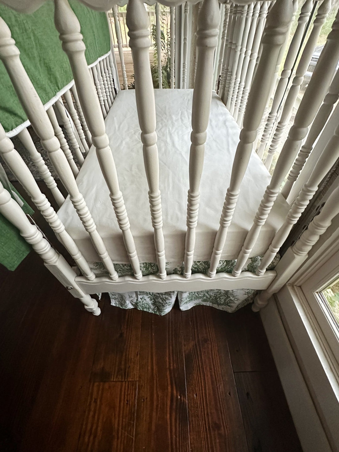 Detail of the green toile crib skirt hemline below the white crib rail