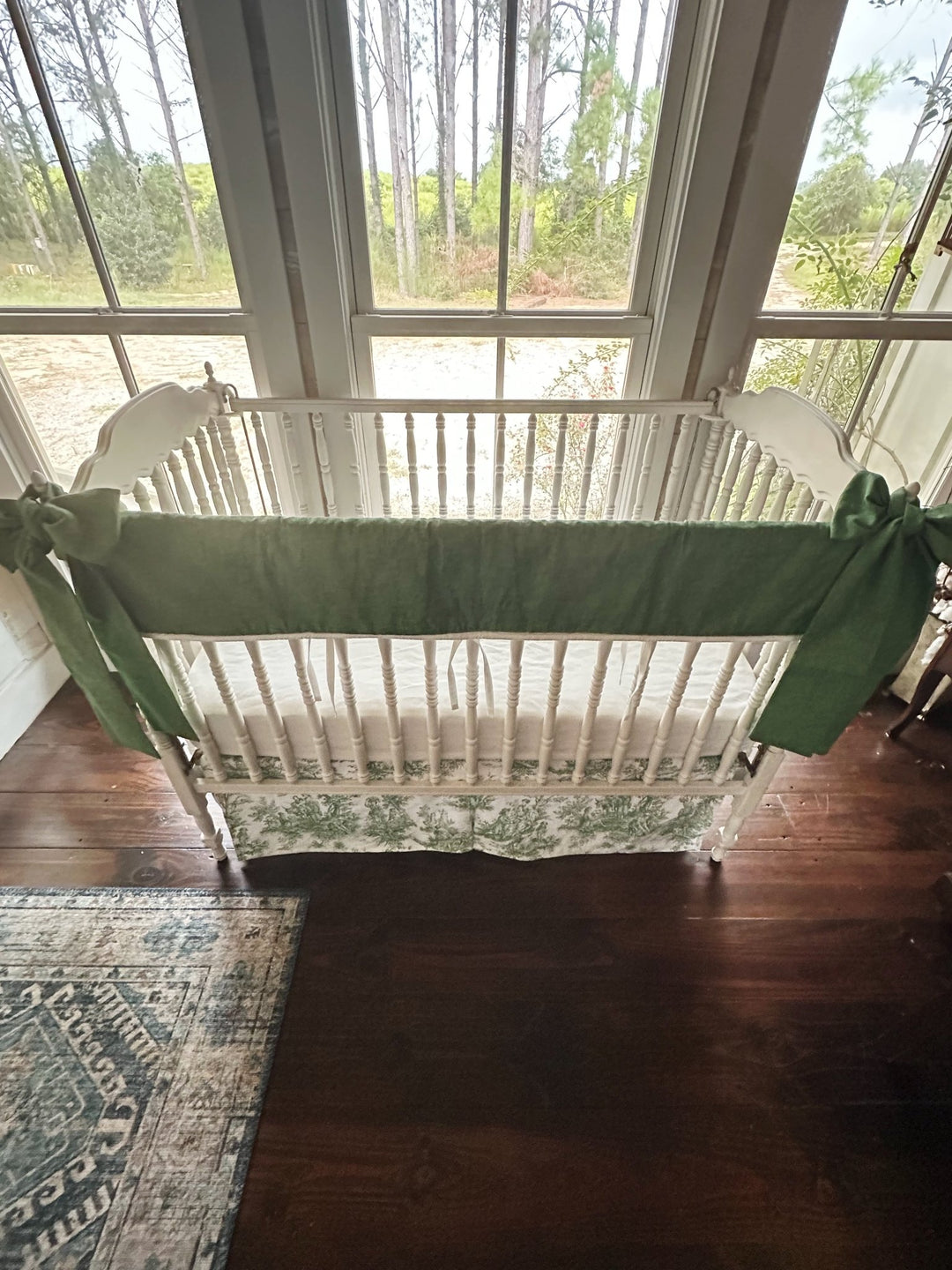 Overhead view of the full green toile and pine green crib bedding set with bows tied at both ends