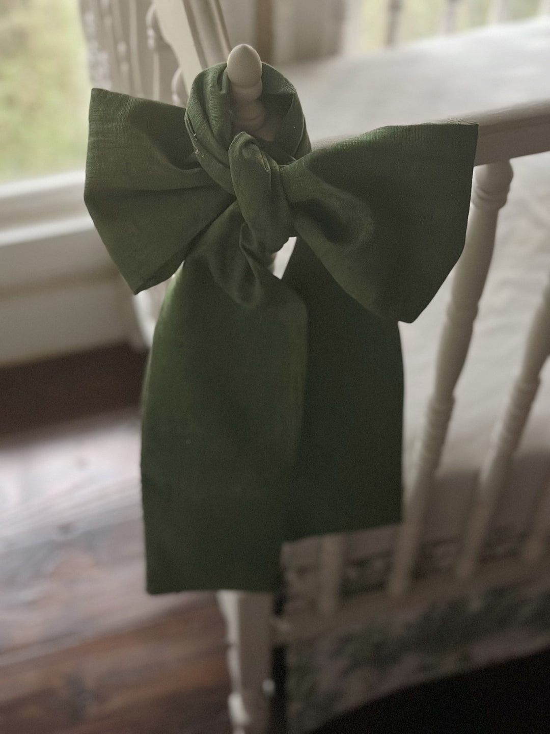 Detail of the knot where the cypress green sash is tied over the crib finial