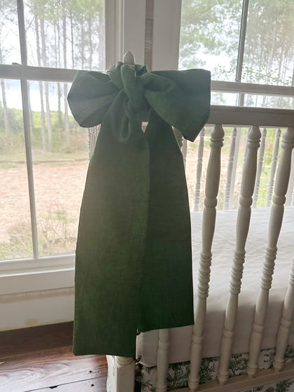 Large cypress green crib bow tied to a white crib post with long sash tails hanging past the rail