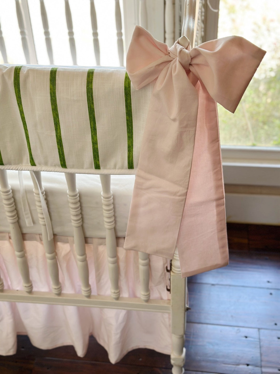 Close view of a baby pink sash knotted at the corner post beside the brushed green stripes