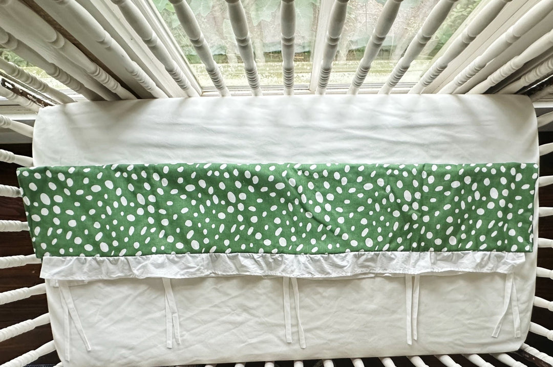 Overhead view of the rail cover folded over the crib rail, showing the plain white back panel