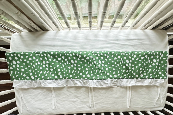 Overhead view of the rail cover folded over the crib rail, showing the plain white back panel