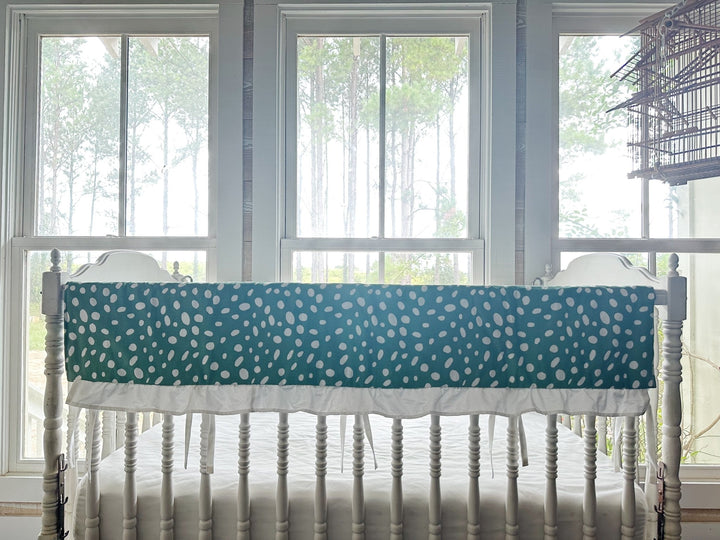 The dot rail cover seen straight on with its white ruffle and slim ties between the spindles