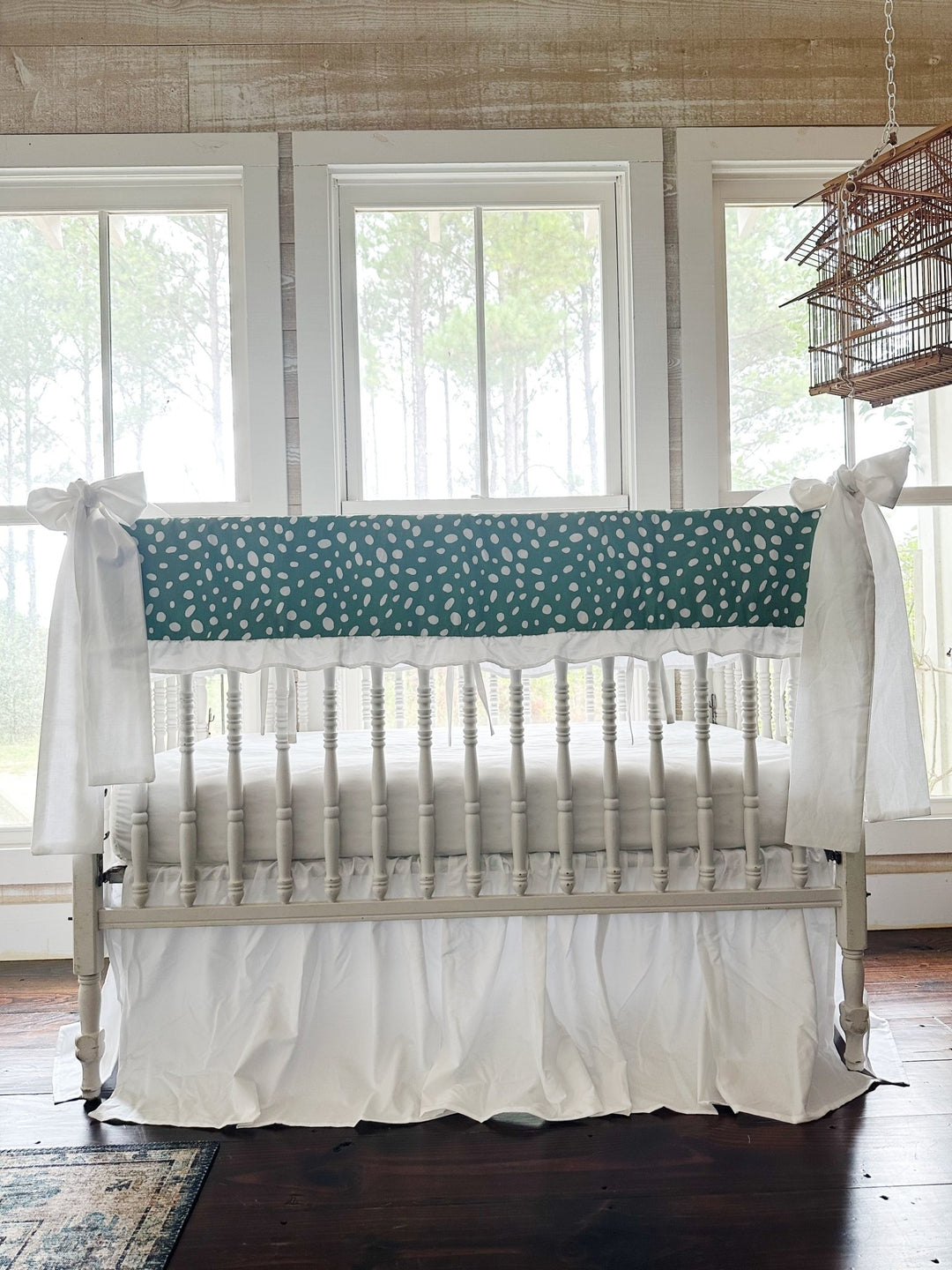 Straight-on view of the green dot crib set with both white bows on the front posts