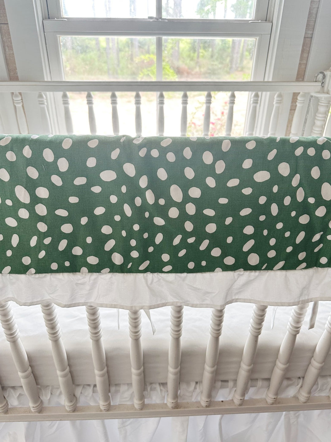 Close view of the irregular white spots on deep green cotton above the gathered white ruffle