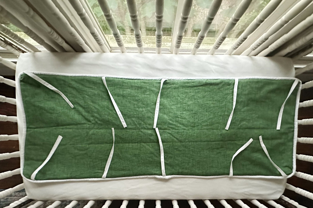Underside of the cypress green crib rail cover showing the white lining and slim white fabric ties