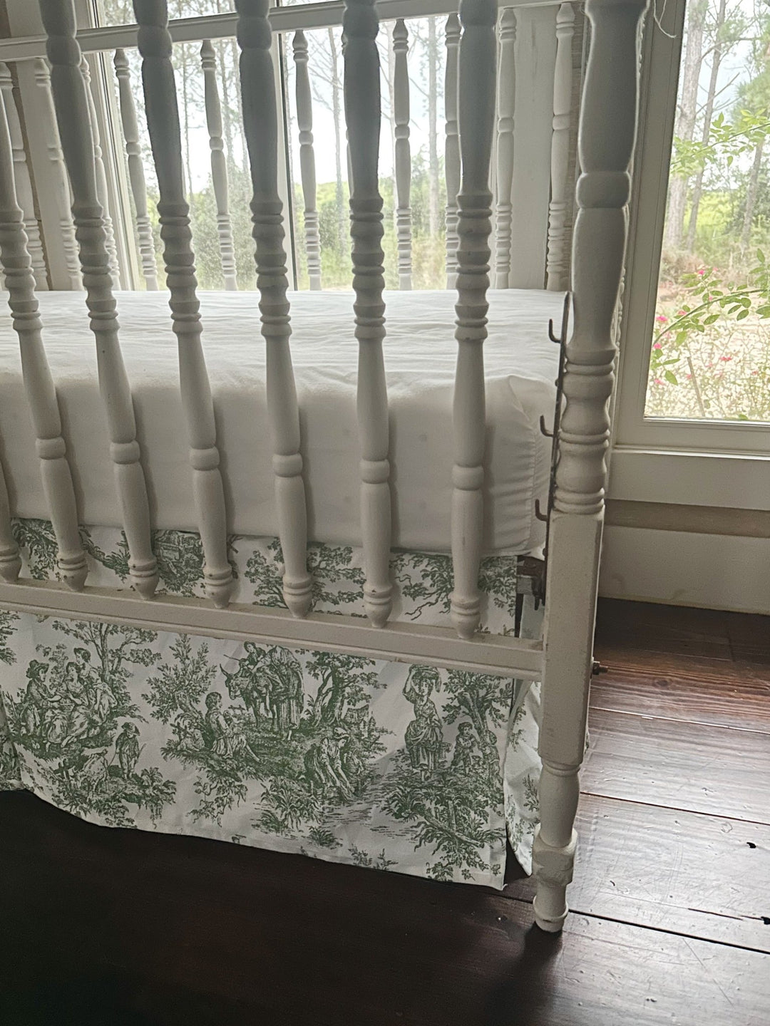 Close view of the green toile print and the pleated center panel of the crib skirt