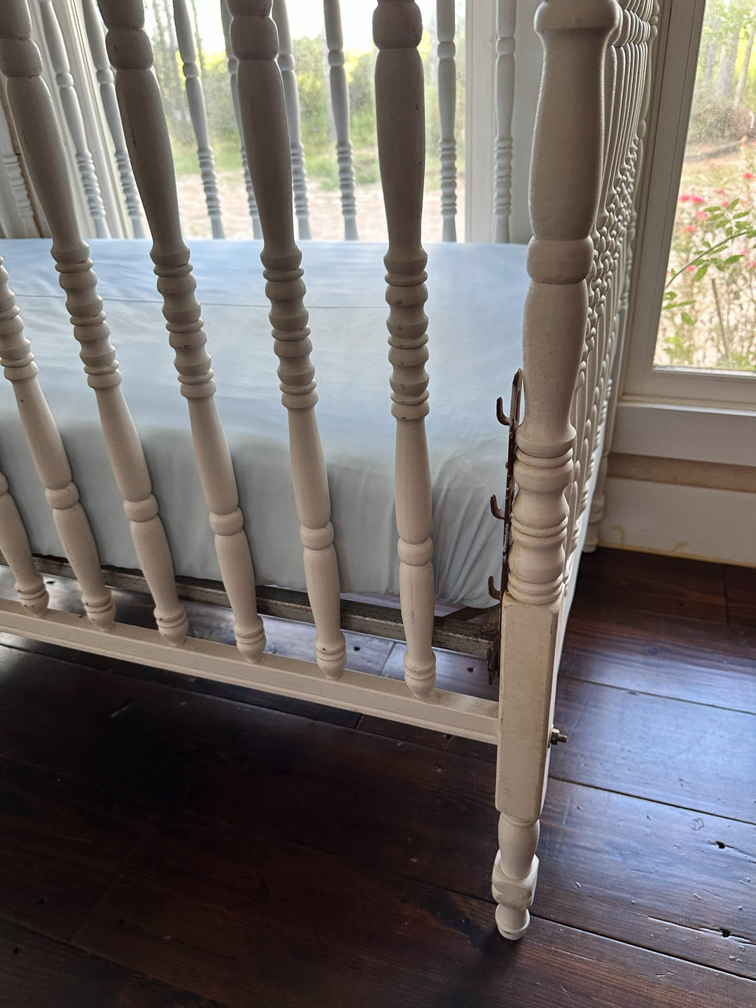 Close view of the crib rail and spindles with the Heirloom Blue fitted crib sheet fitted snugly beneath - High Cotton Textile