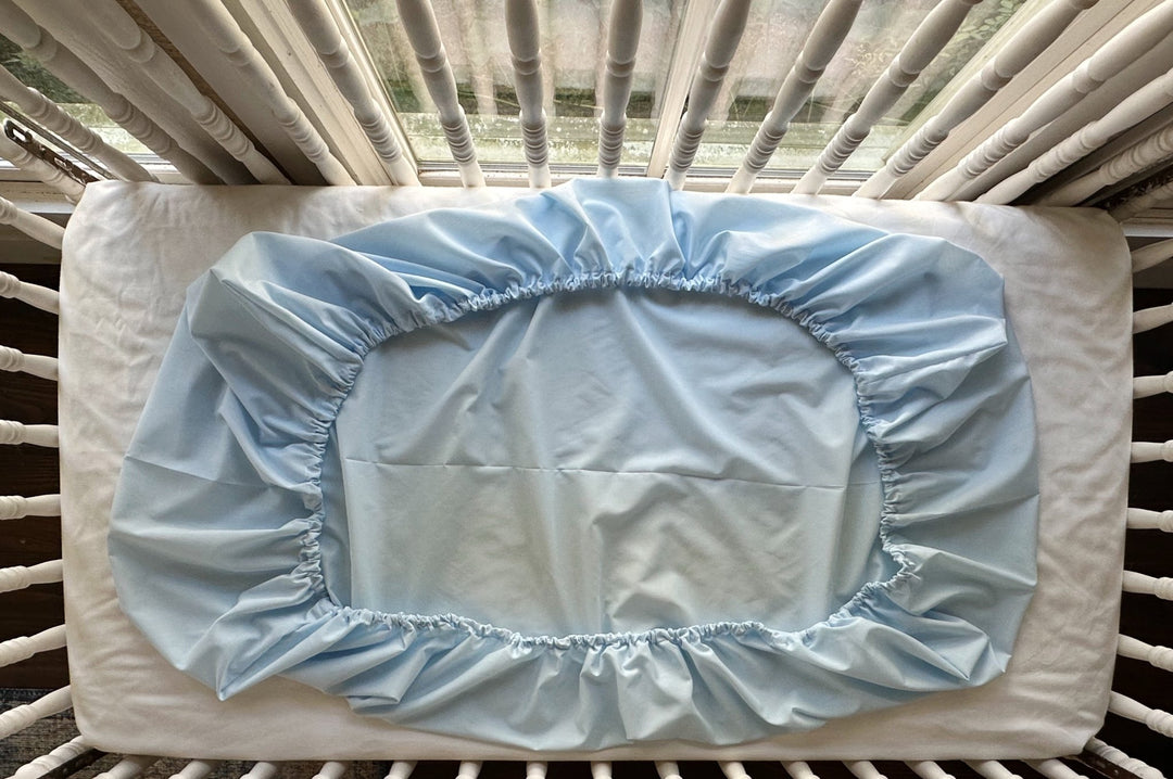 Underside of the Heirloom Blue fitted crib sheet showing elastic gathered all the way around the mattress - High Cotton Textile
