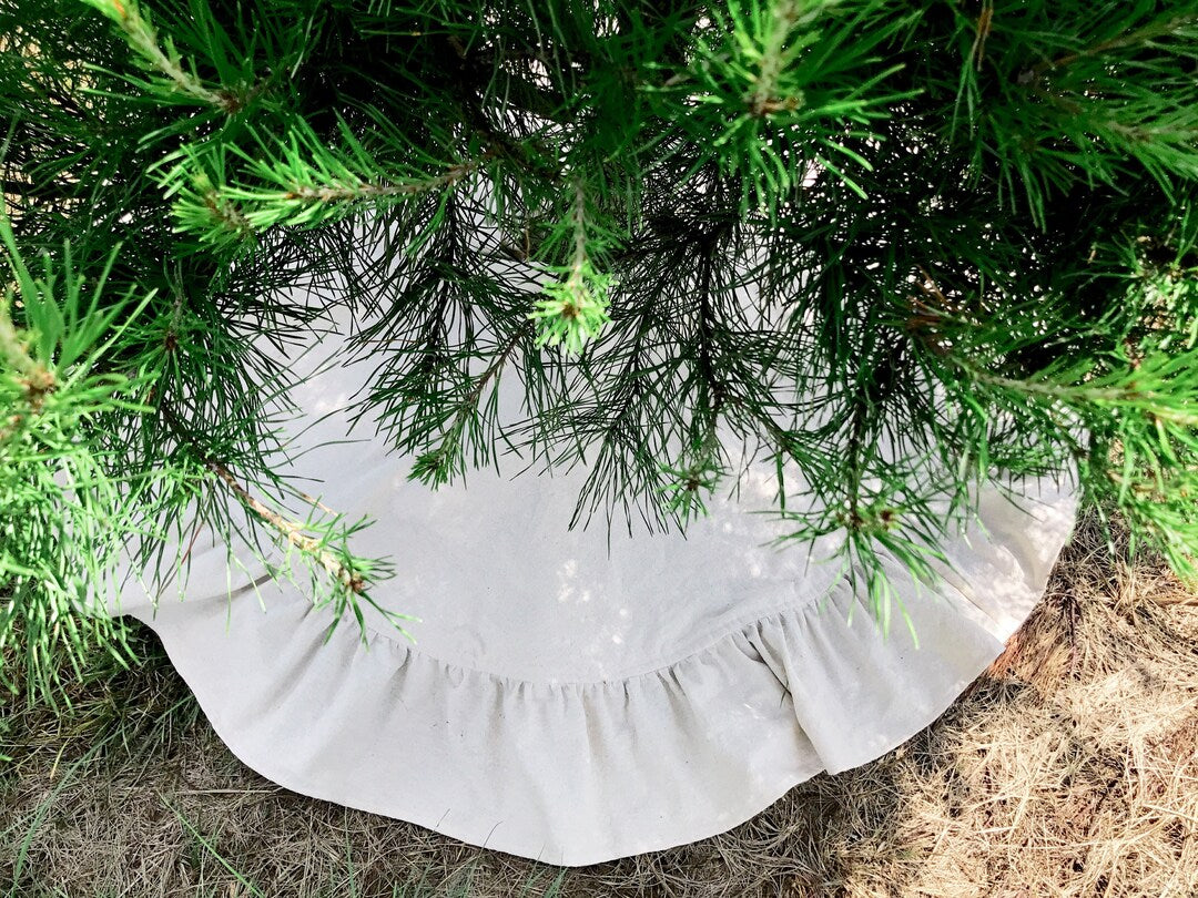 Full osnaburg ruffle peeking out under low pine branches on dry grass