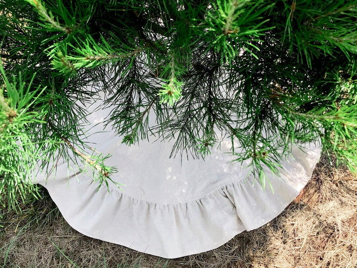 Full osnaburg ruffle peeking out under low pine branches on dry grass