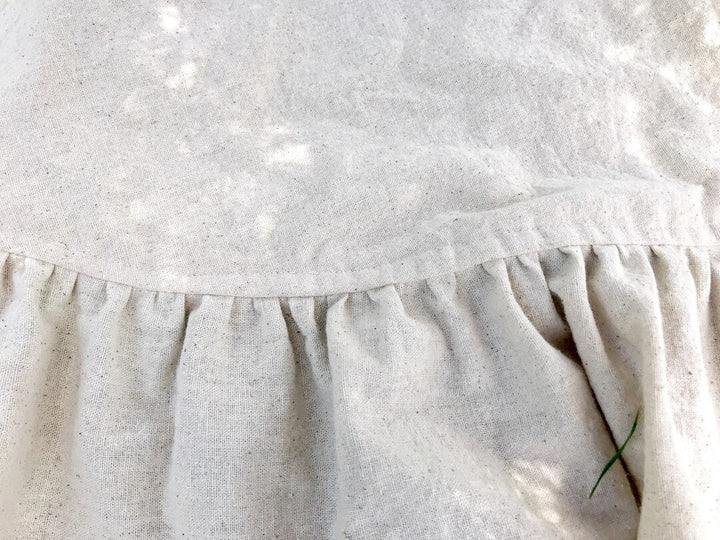 Close-up of the gathered ruffle seam on the natural osnaburg tree skirt, showing the flecked cotton weave