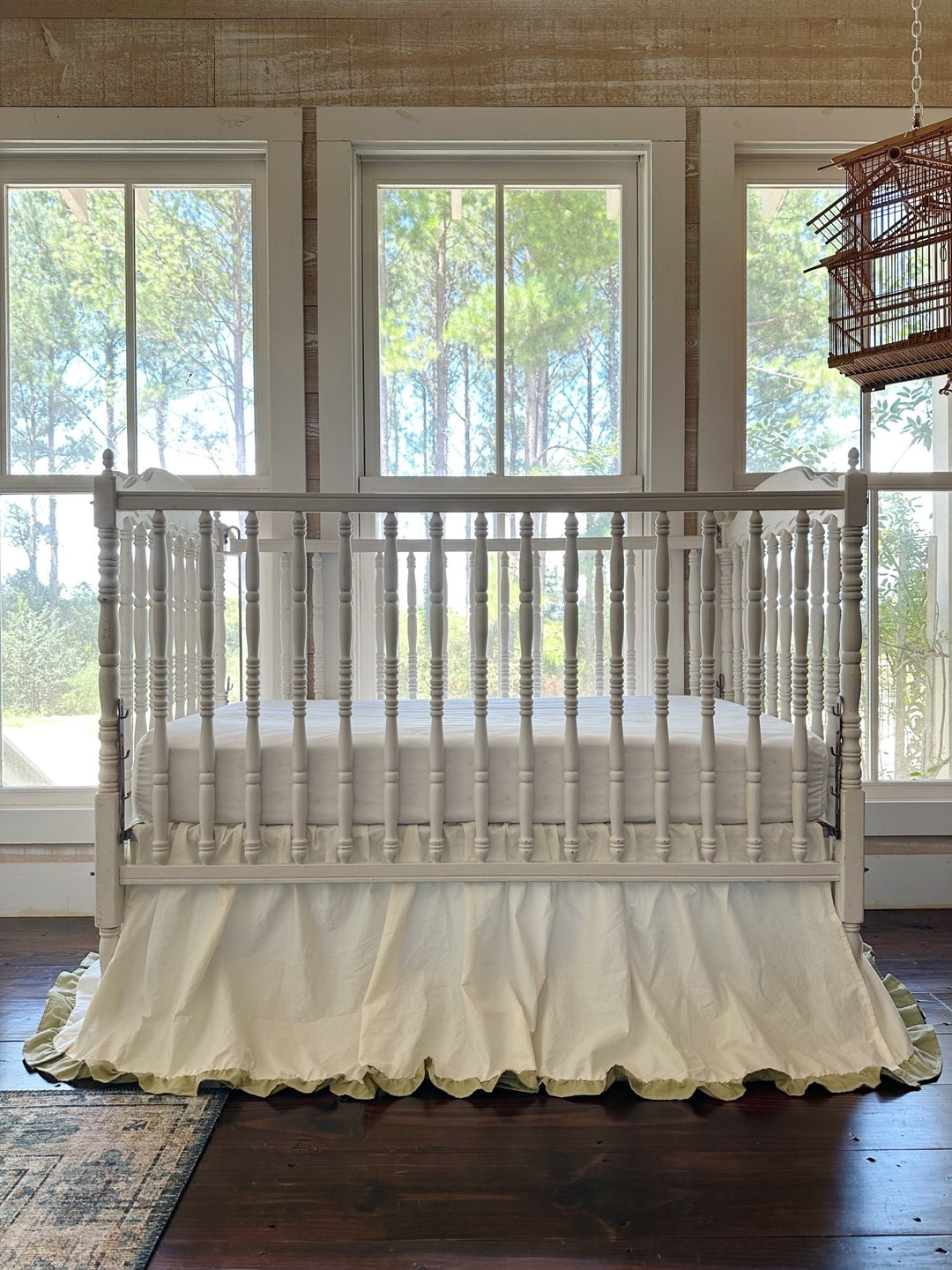 Ivory and sage green ruffled cotton crib skirt shown front on, gathered on all four sides with a 22 inch drop