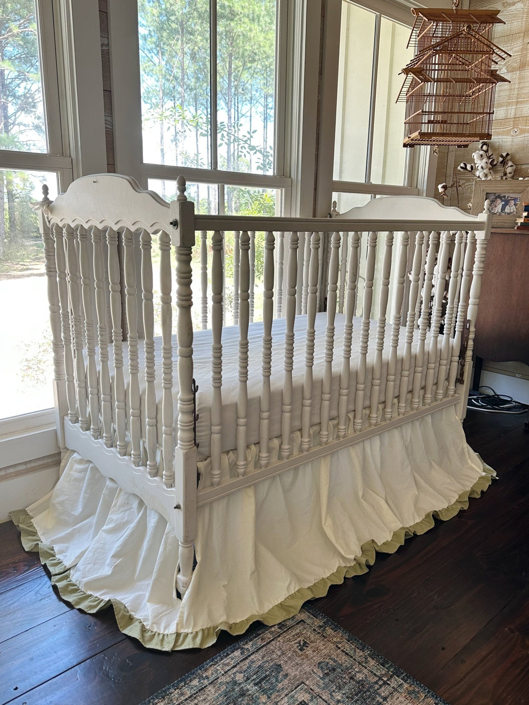 Ivory ruffled crib skirt with sage green ruffle hem on a white spindle crib in a farmhouse nursery - High Cotton Textile
