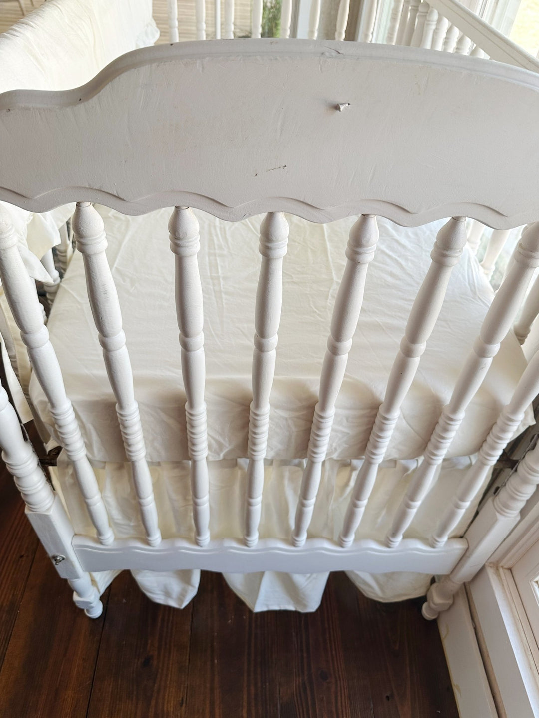 Close overhead view of the scalloped headboard spindles with the ivory skirt gathered beneath the mattress