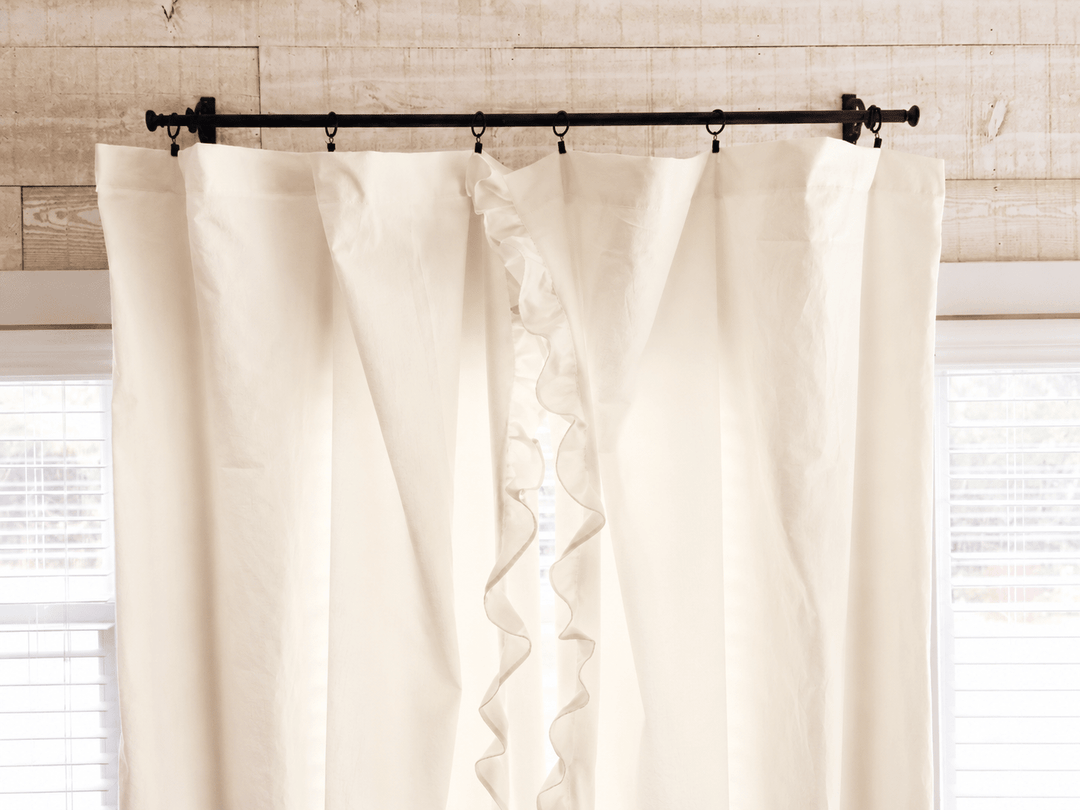 Top of the ivory ruffled curtain panels on iron rings, showing the gathered heading against shiplap - High Cotton Textile