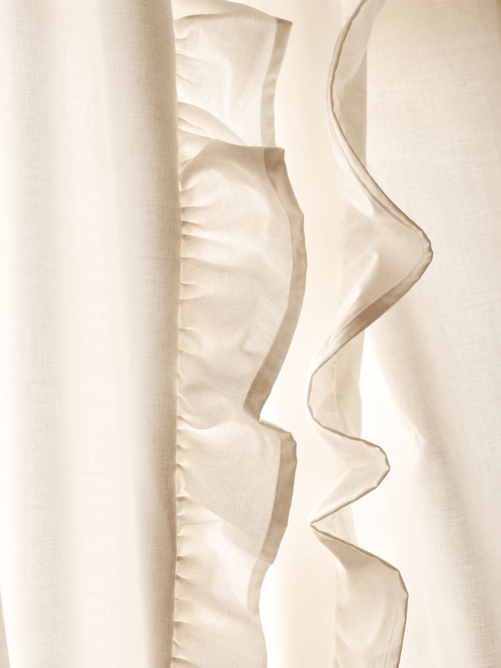 Close view of the ruffle on the leading edge of an ivory curtain panel, backlit so the washed cotton weave shows - High Cotton Textile