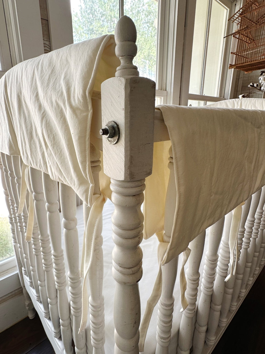 Ivory rail covers meeting at the crib corner post beside the turned wooden finial