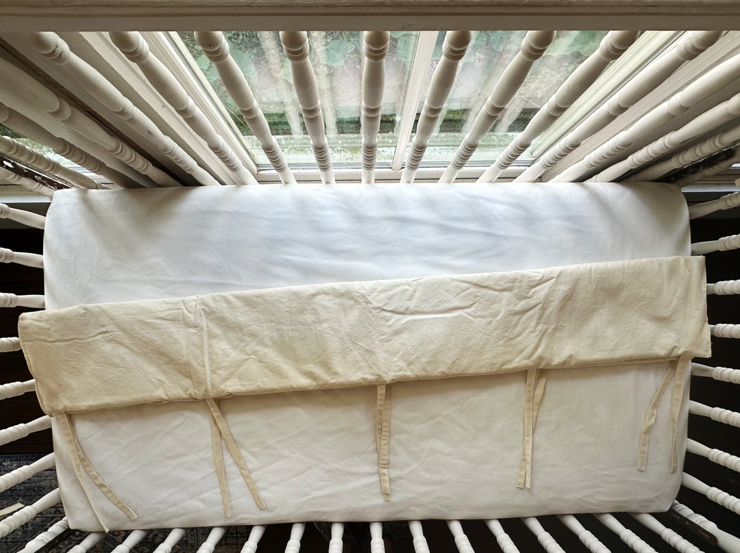Overhead view of a Natural short rail cover folded over the end top rail of a spindle crib