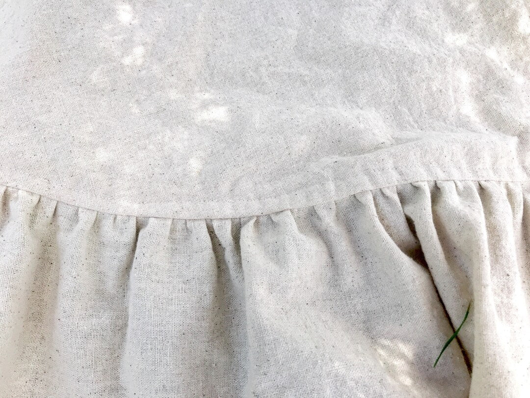 Close-up of the gathered ruffle seam on the natural osnaburg tree skirt, showing the flecked cotton weave