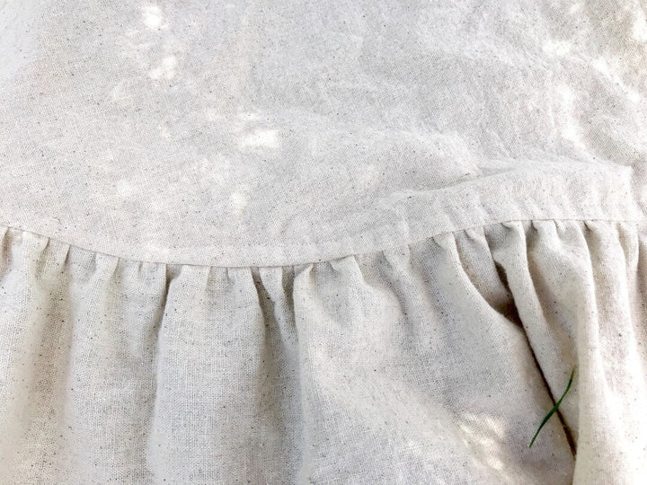 Close-up of the gathered ruffle seam on the natural osnaburg tree skirt, showing the flecked cotton weave