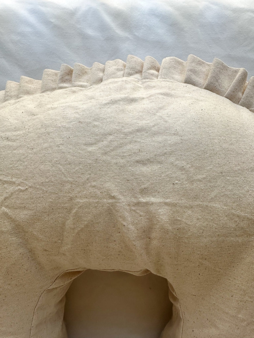 Top of the Natural Osnaburg nursing pillow cover above the inner curve, with the pleated ruffle along the back edge
