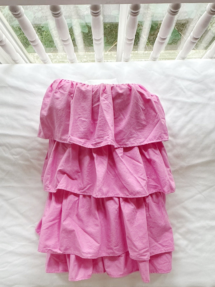 Parfait pink tiered crib skirt folded on a white crib mattress, showing the stacked gathered tiers