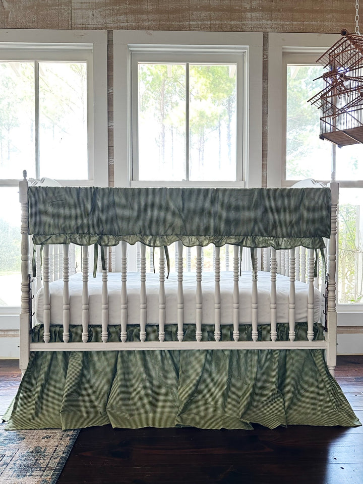 Pine green gingham crib rail cover and farmhouse crib skirt on a white spindle crib