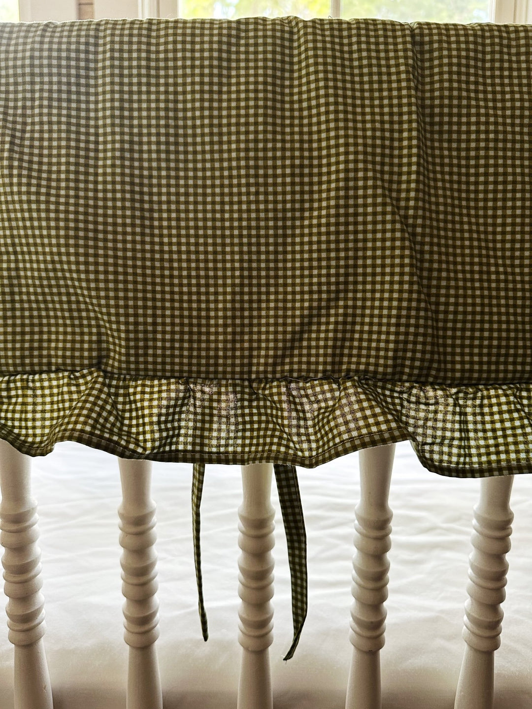 Close-up of the small green gingham check and gathered ruffle on the crib rail cover