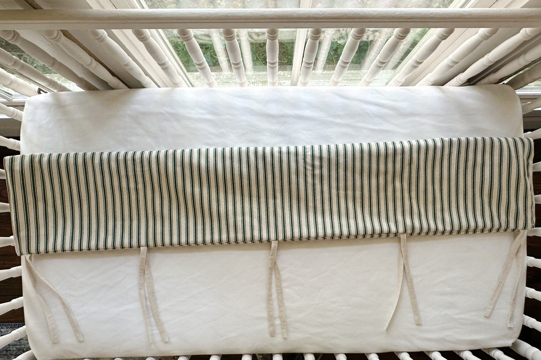 Looking down at the cover folded over the top rail, ties knotted loose against the white sheet