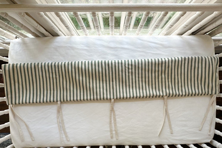 Looking down at the cover folded over the top rail, ties knotted loose against the white sheet