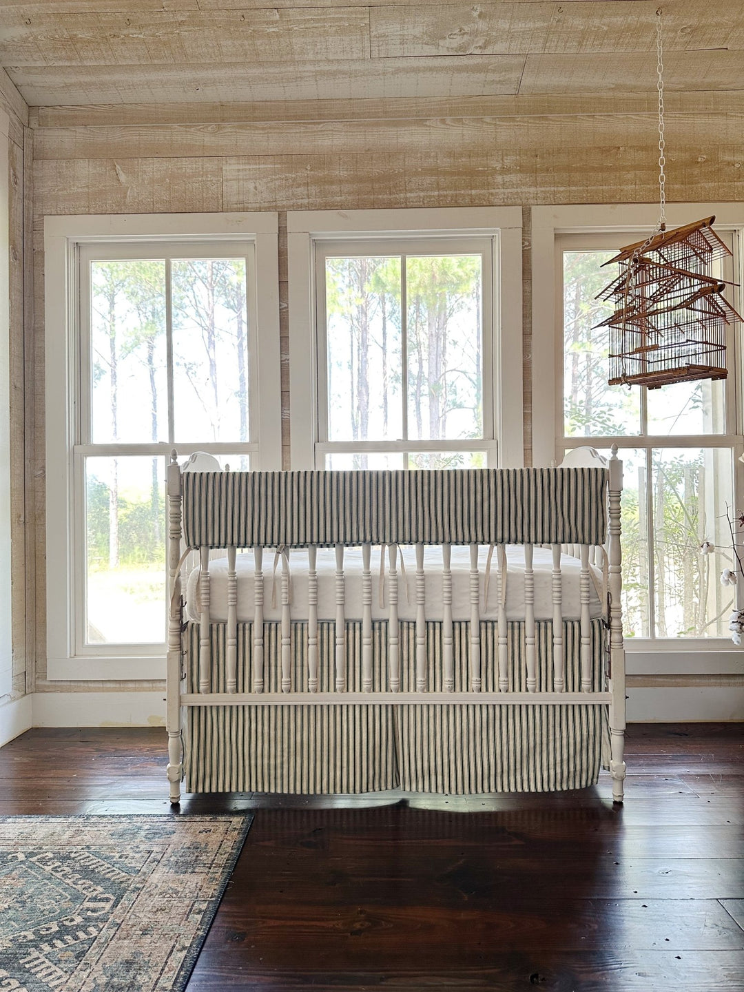 The green ticking set in a pine-paneled room with three windows and a hanging birdcage