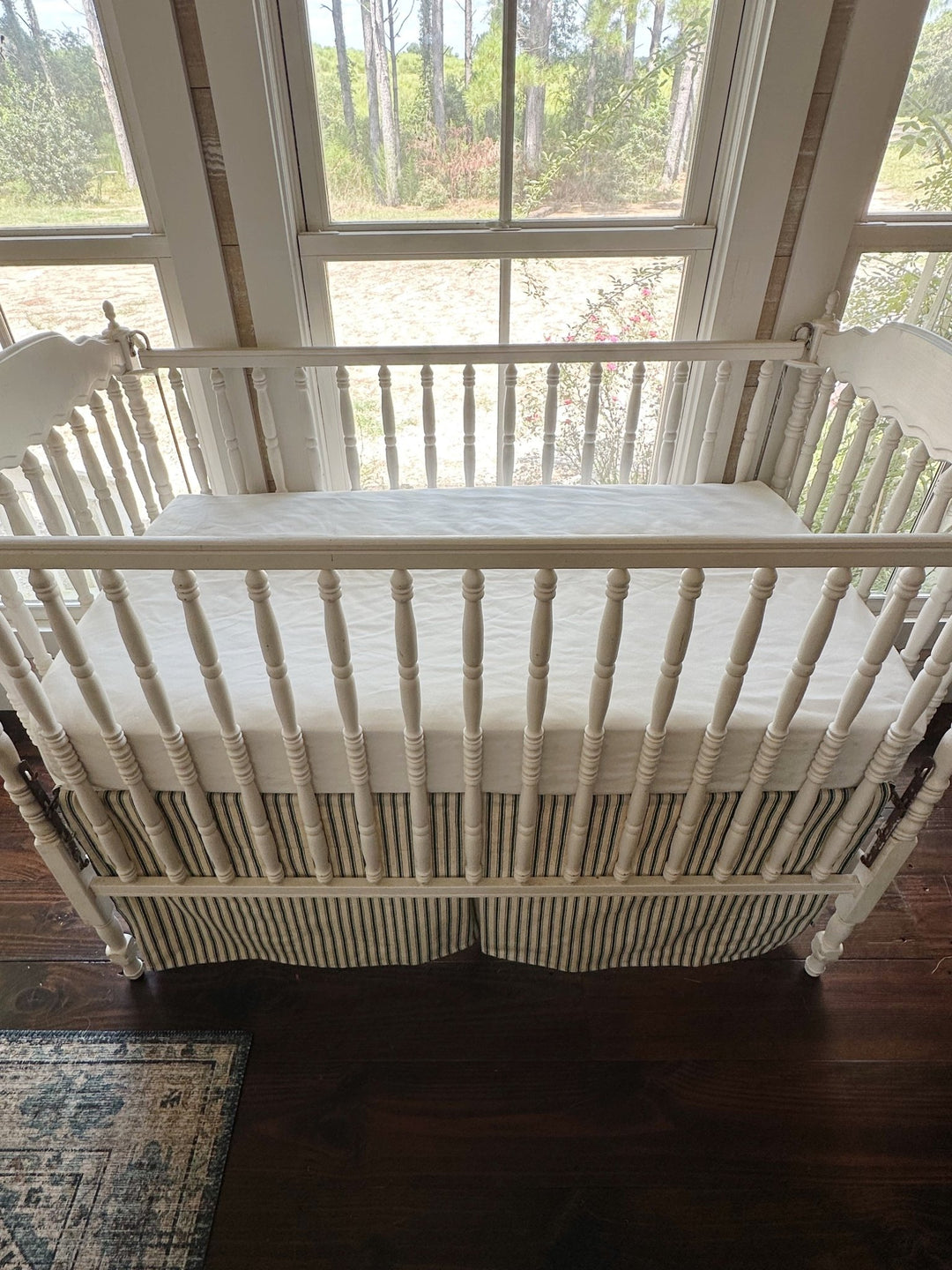 Looking down on the crib with the ticking skirt hanging below the white sheet