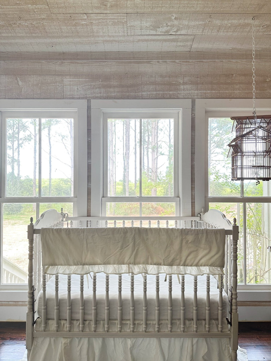 Wide nursery view of the porcelain rail cover on the crib in a pine-panelled room