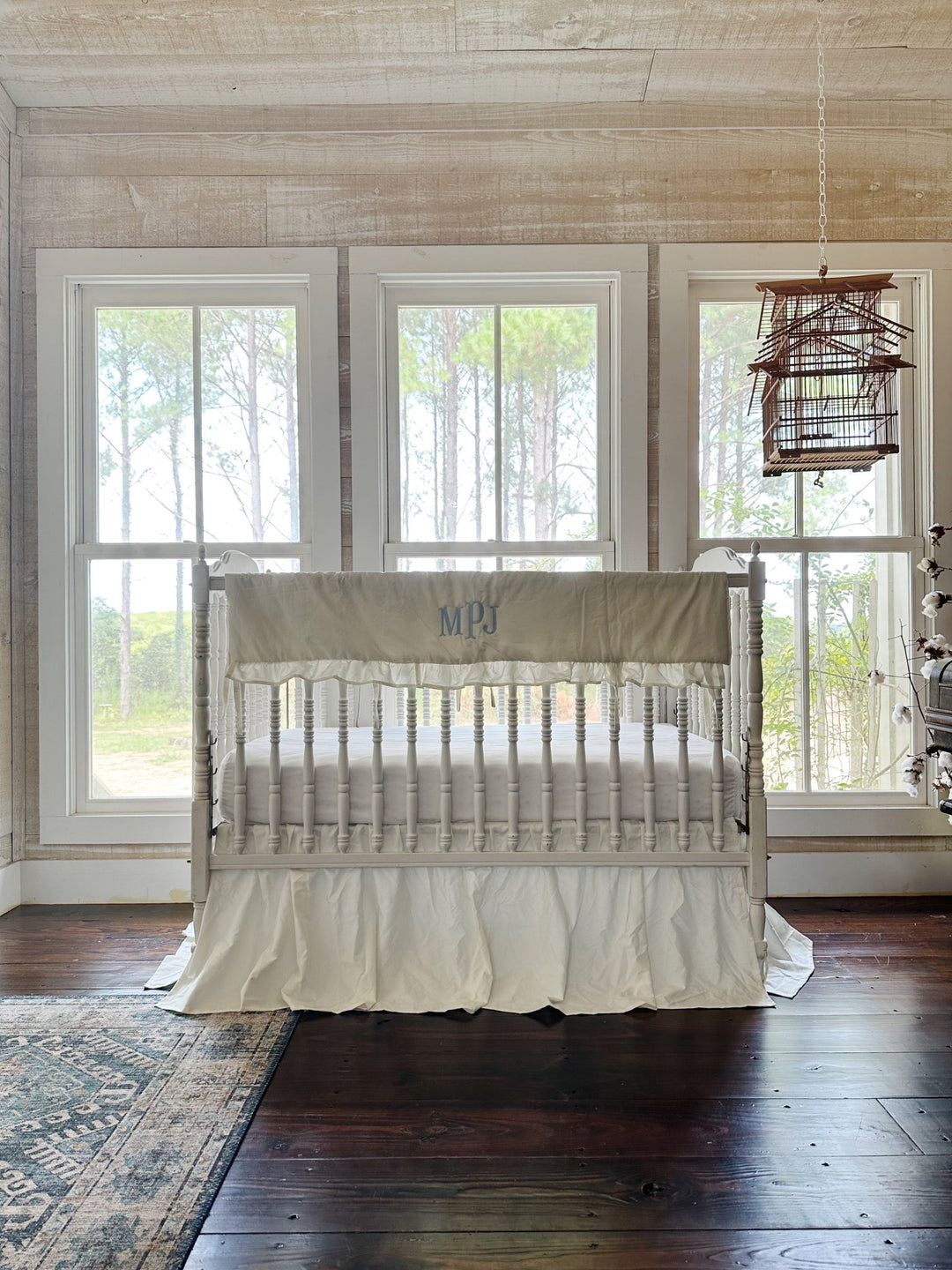 Porcelain ruffled crib rail cover and matching farmhouse crib skirt on a white spindle crib