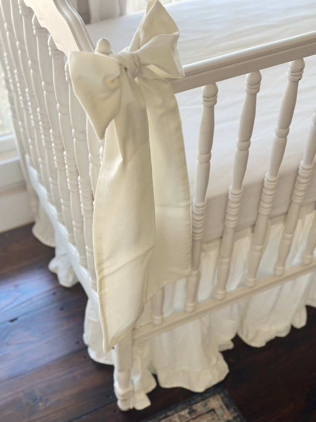 Porcelain bow tied at the corner post above the scalloped end rail, ruffled skirt gathered to the floor below