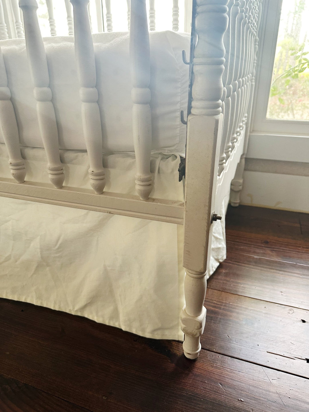 Split corner of the porcelain crib skirt wrapping cleanly around a turned crib leg - High Cotton Textile