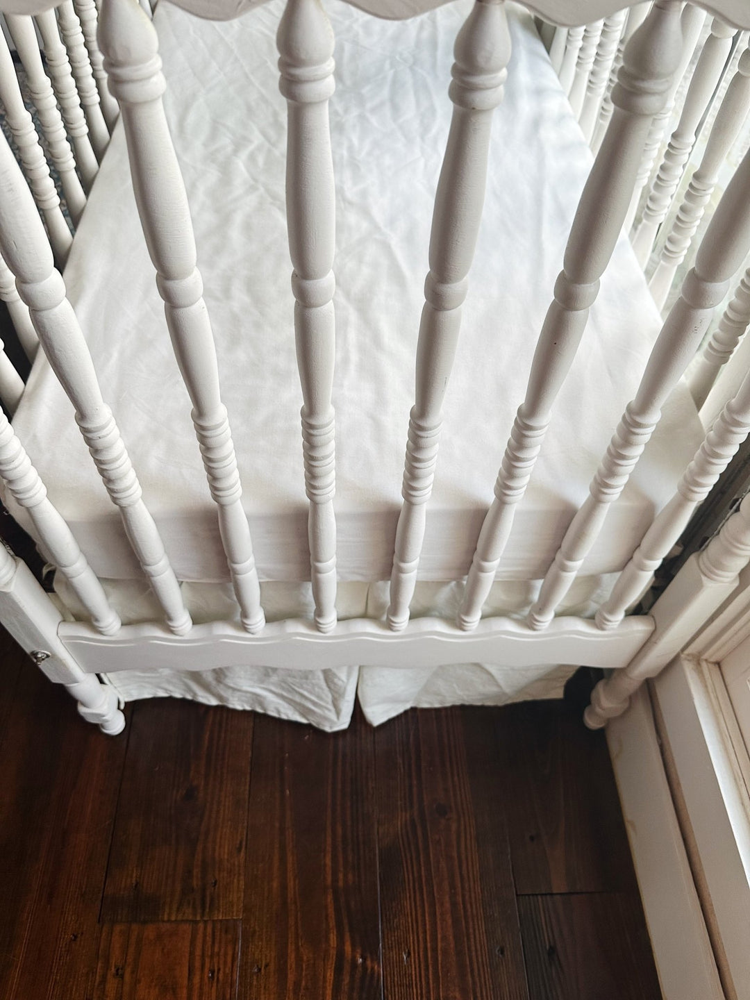Foot of the crib showing the porcelain skirt hem falling to the floorboards - High Cotton Textile