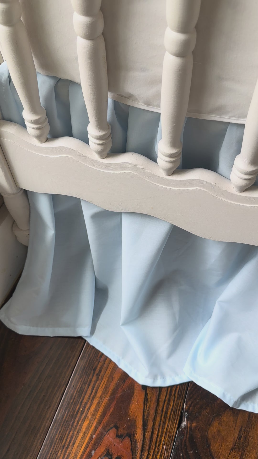 Heirloom blue farmhouse crib skirt and two large crib bows styled on a white spindle crib.
